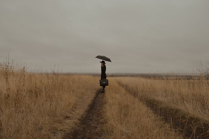 冬の曇り空の下で一人ポツンと黒い傘をさす喪服の男