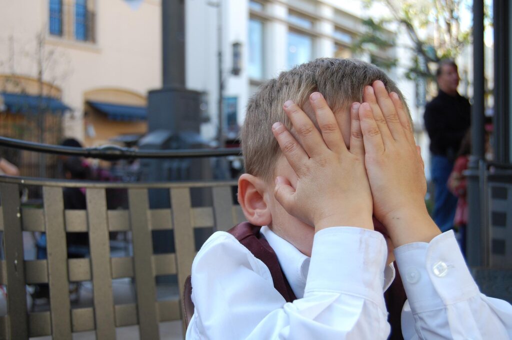 恥ずかしくて両手で顔を隠している少年